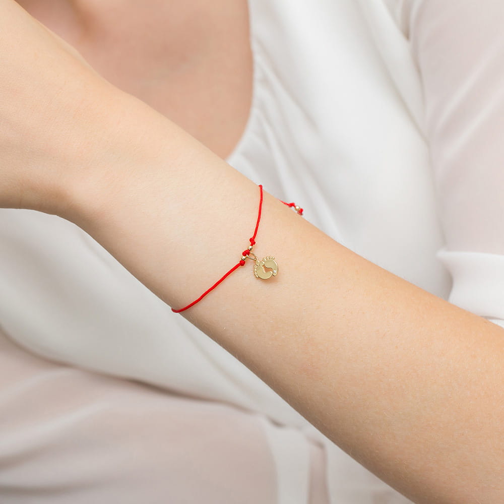 Bransoletka na czerwonym sznurku z motywem stópek